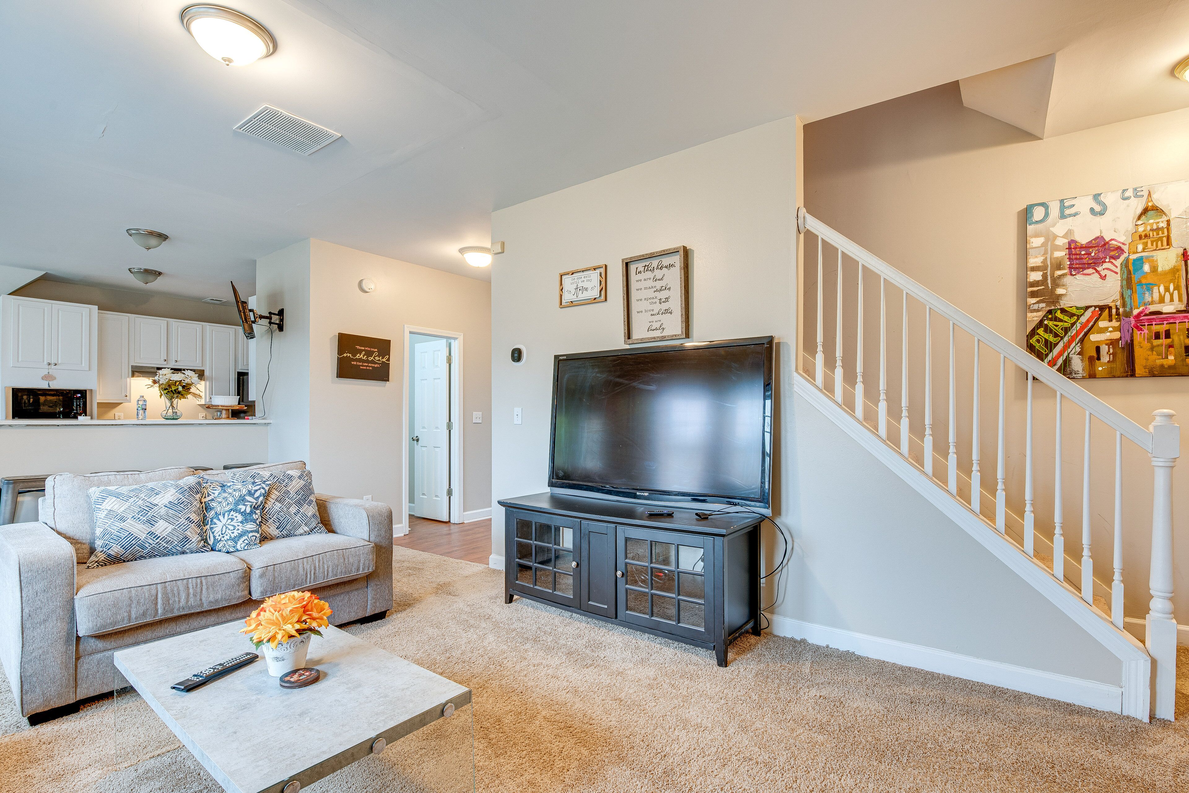 A living room with a sofa, coffee table, TV, and a staircase.
