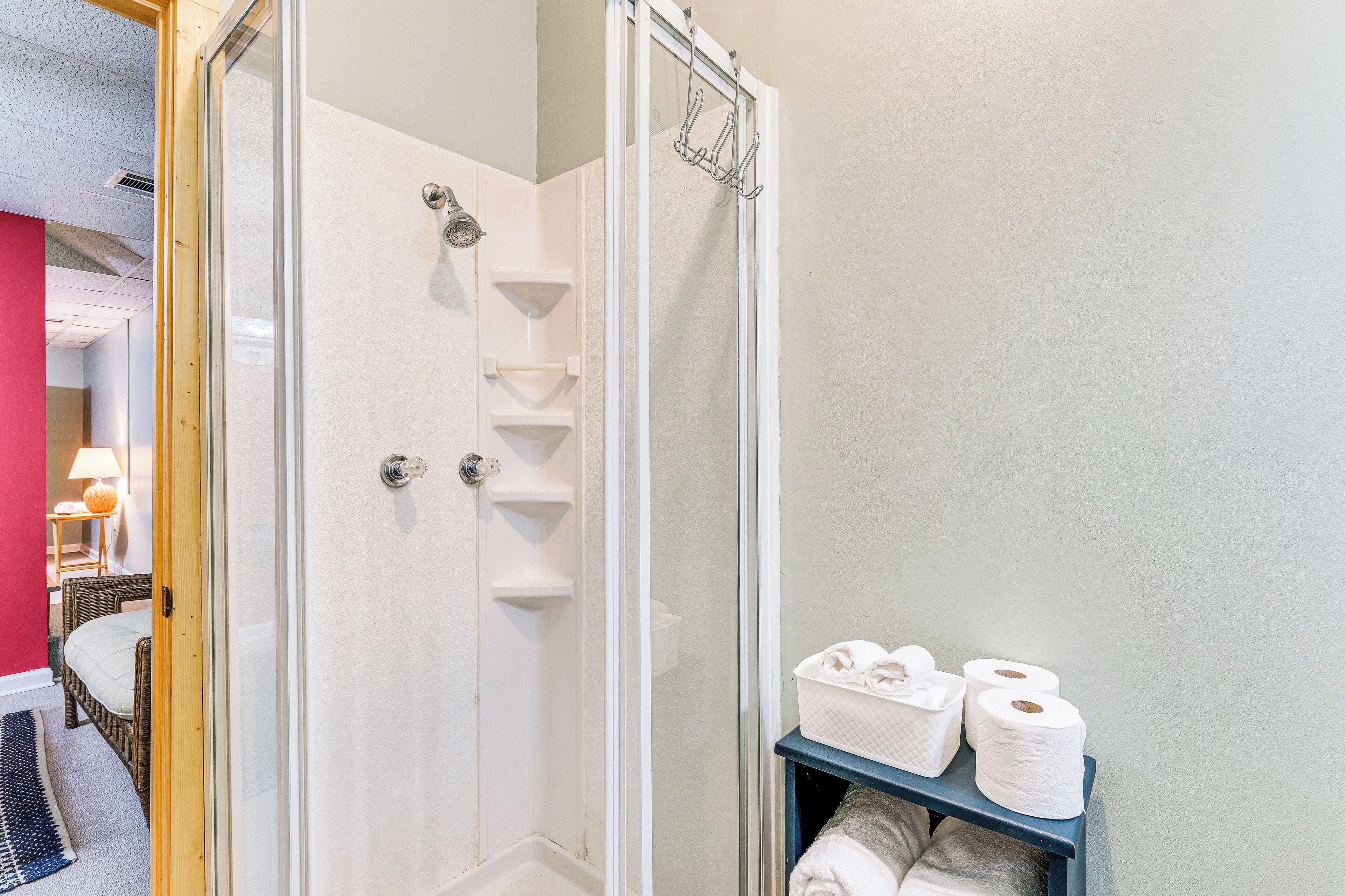 Eine Dusche mit Glastür, ein Handtuchhalter und ein Ablagefach mit Toilettenartikeln.