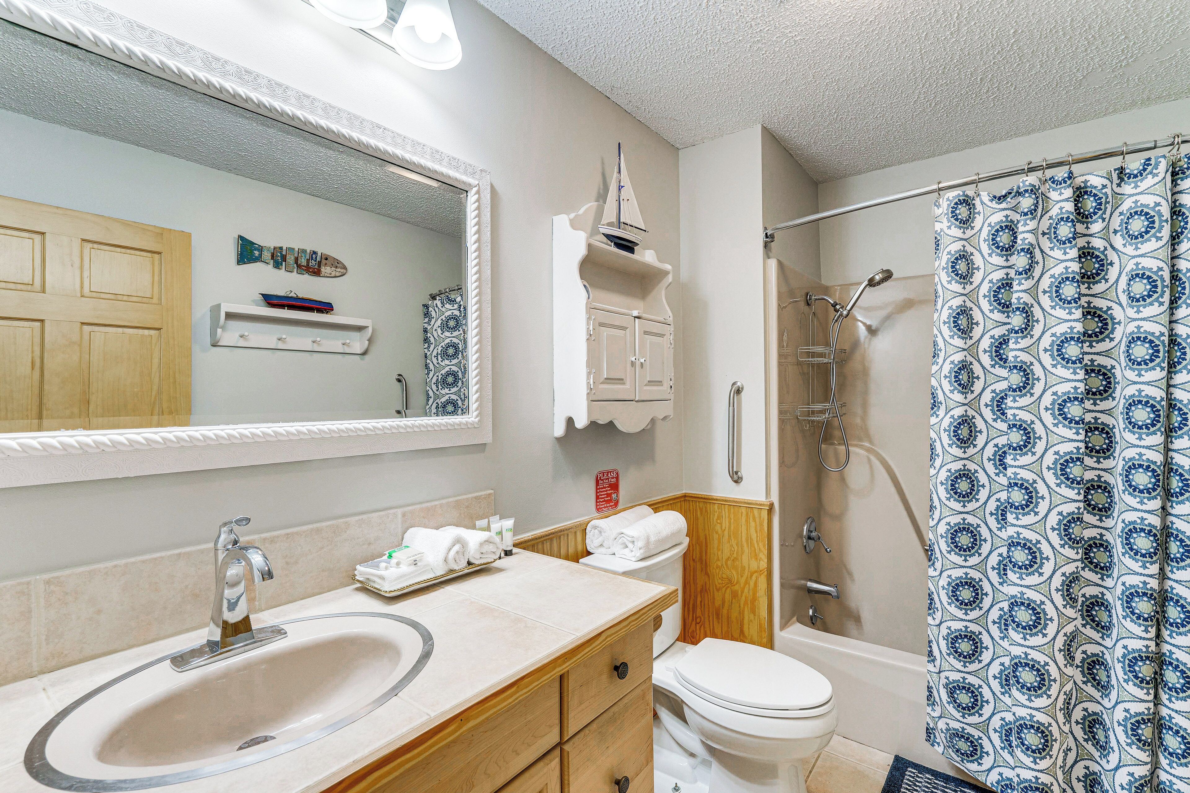 A bathroom with a sink, mirror, toilet, and shower.