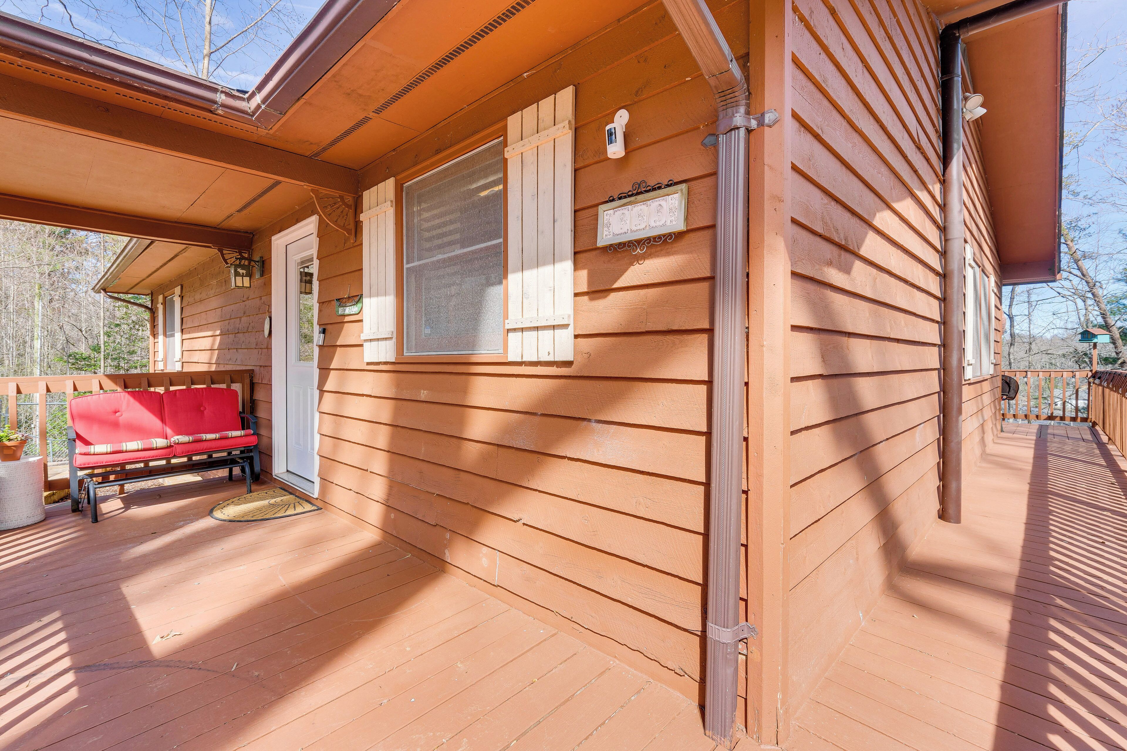 A wooden cabin with a porch, a red bench, and a door.