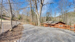 A gravel driveway leading to a wooden cabin with a metal fence on the left. - Pet-friendly Hiawassee Cabin w/ Lake Views & Sauna (Hiawassee)