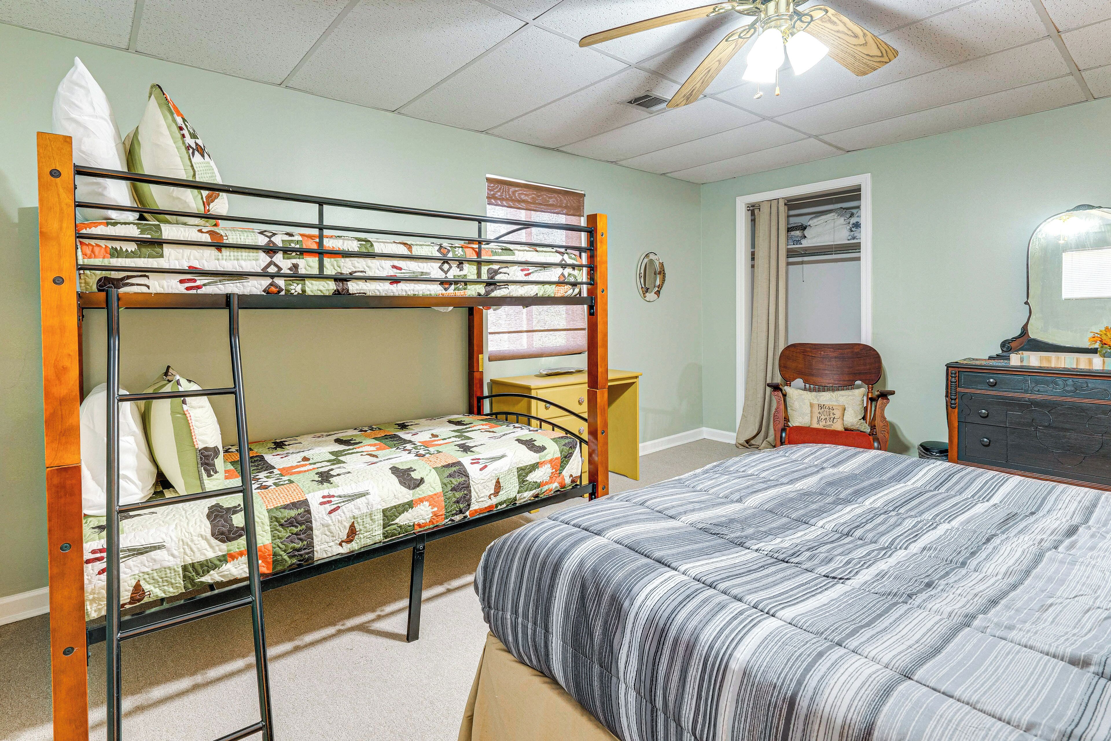 A bunk bed with a quilted mattress, a wooden ladder, and a desk with a chair.
