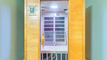 A sauna with a wooden exterior, a glass door, and a control panel on the wall.