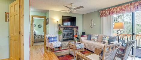 A cozy living room with a fireplace, comfortable seating, and a view of the outdoors.