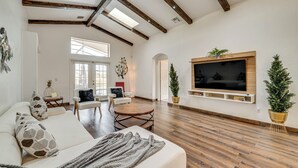 A spacious living room with a large TV, wooden beams, a fireplace, and a cozy seating area.