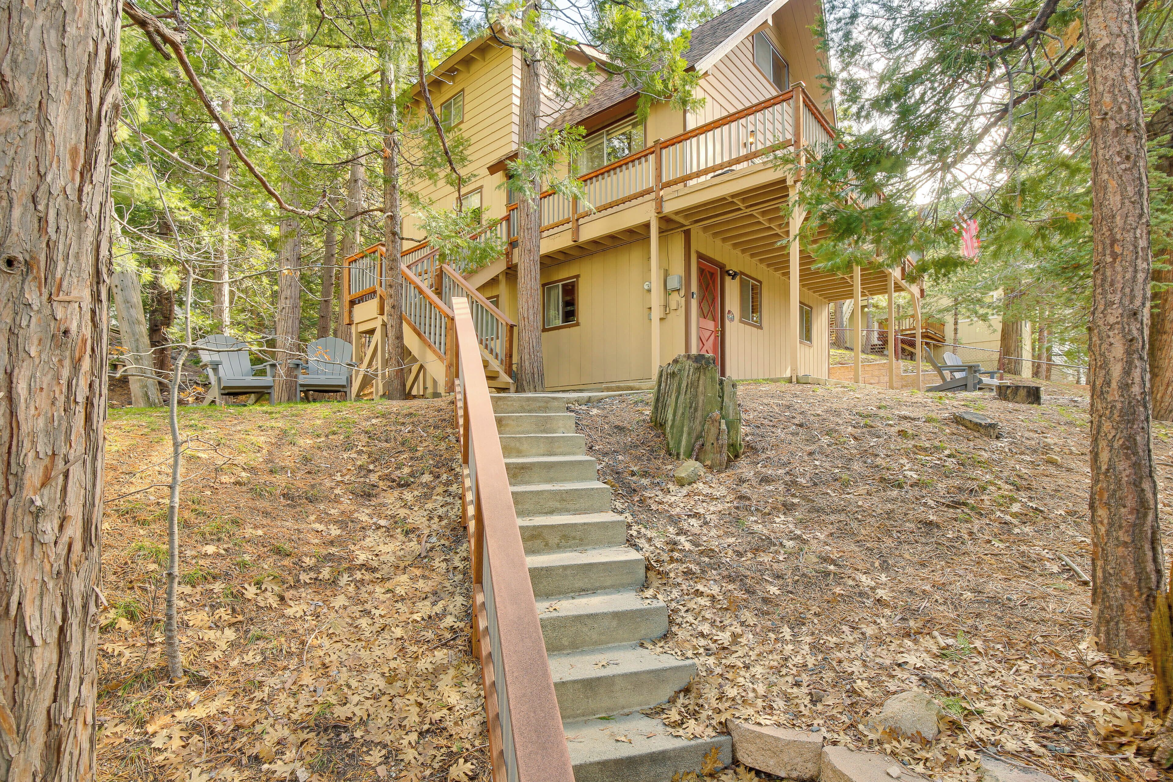 A two-story wooden cabin with a wooden staircase leading to a front porch.