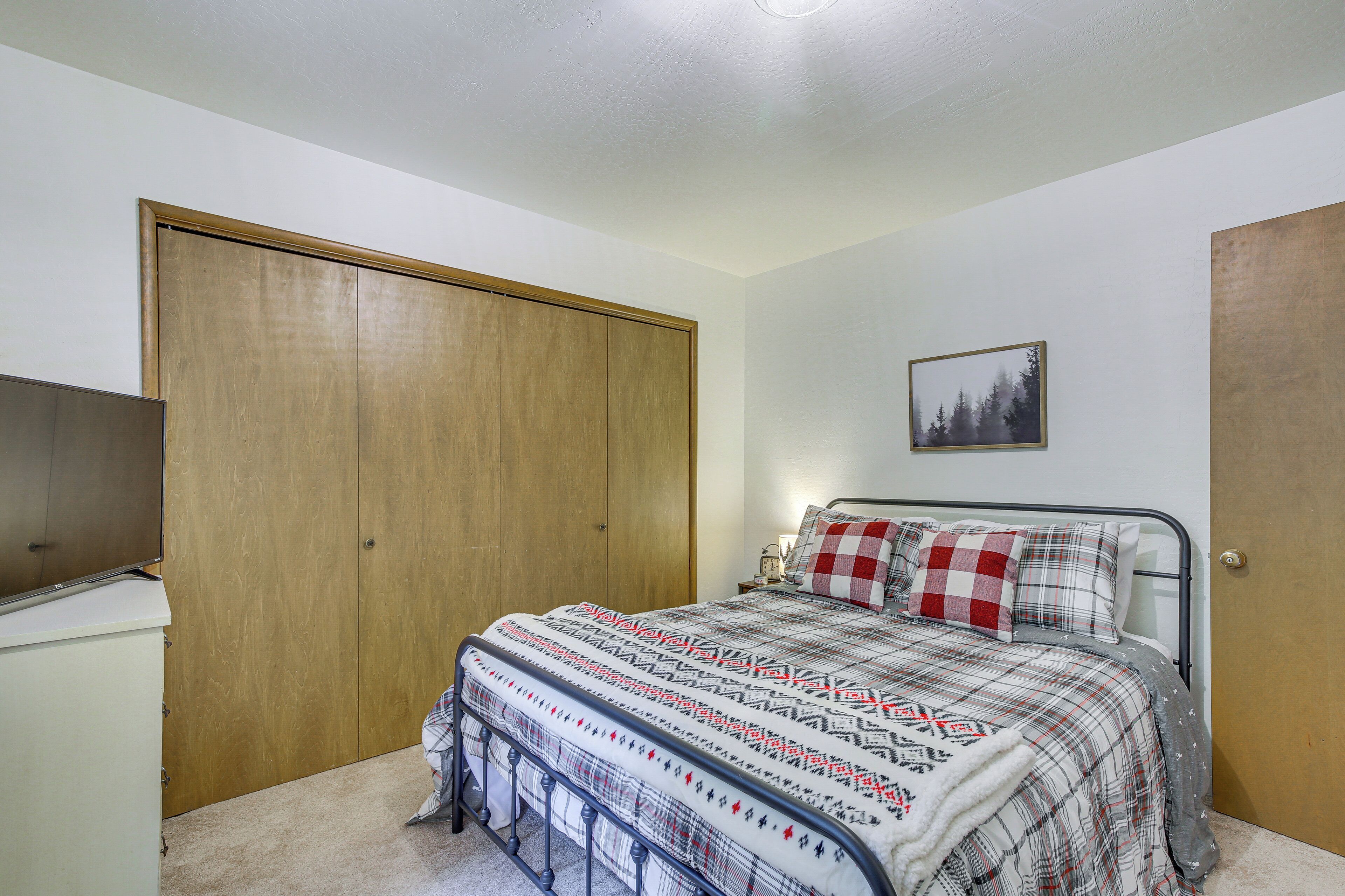 Ein Schlafzimmer mit einem Bett, einem Kleiderschrank, einem Schreibtisch und einem gerahmten Bild an der Wand.