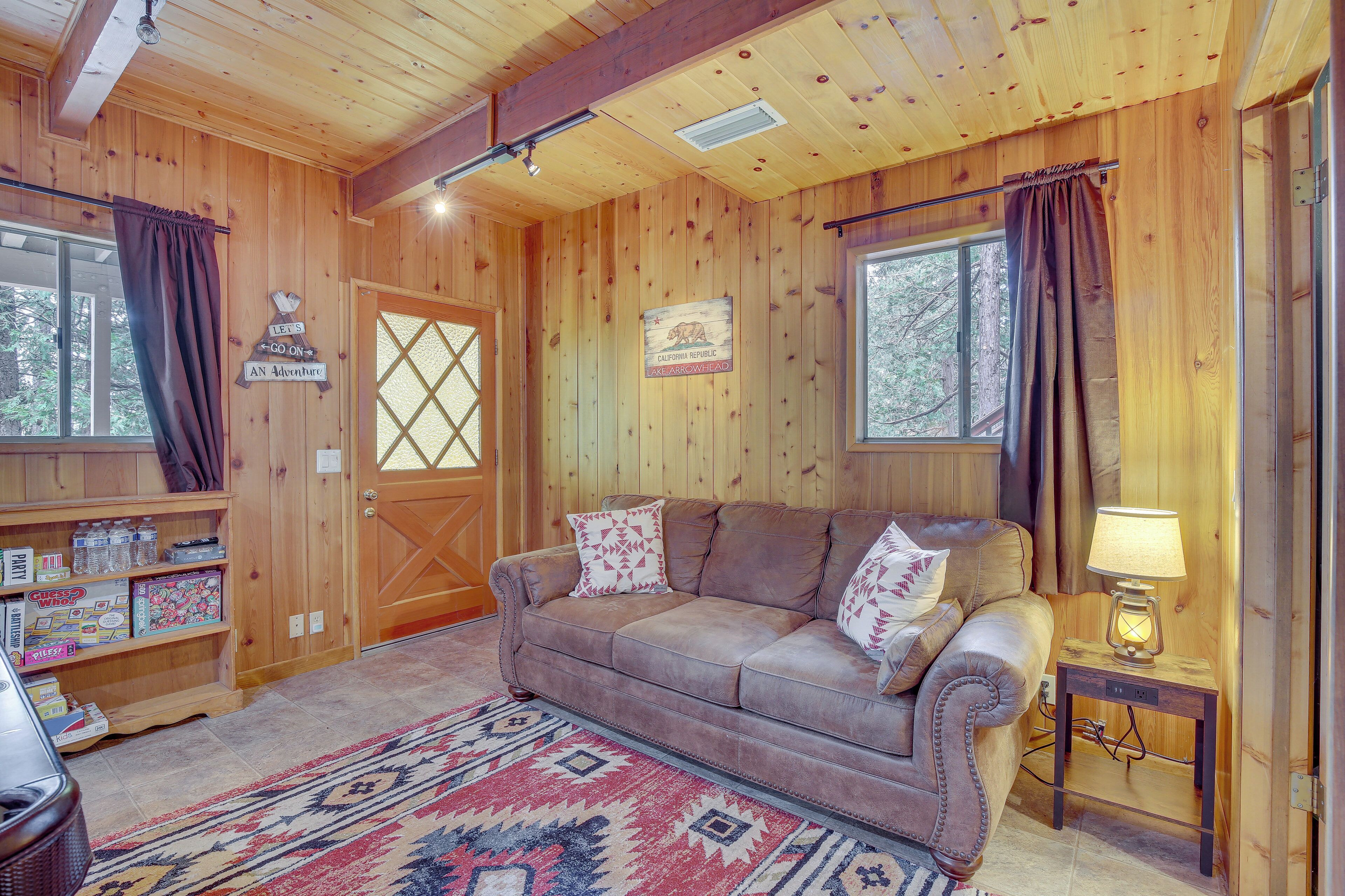 L’intérieur chaleureux d’un chalet, avec un décor en bois, un canapé agrémenté de coussins, un tapis et un panneau décoratif accroché au mur.