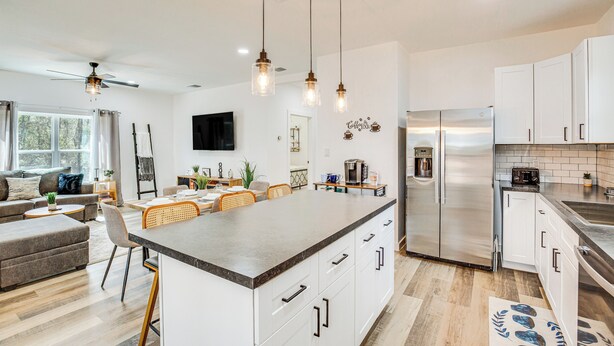 A modern kitchen with a central island, white cabinetry, stainless steel appliances, and pendant lighting. - Winnsboro Barndominium w/ Fire Pit & Large Deck! (Winnsboro)