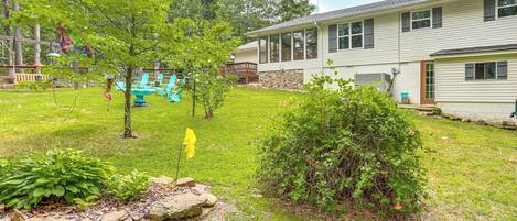 A residential property with a well-maintained lawn, a stone wall, and a play area with blue chairs.