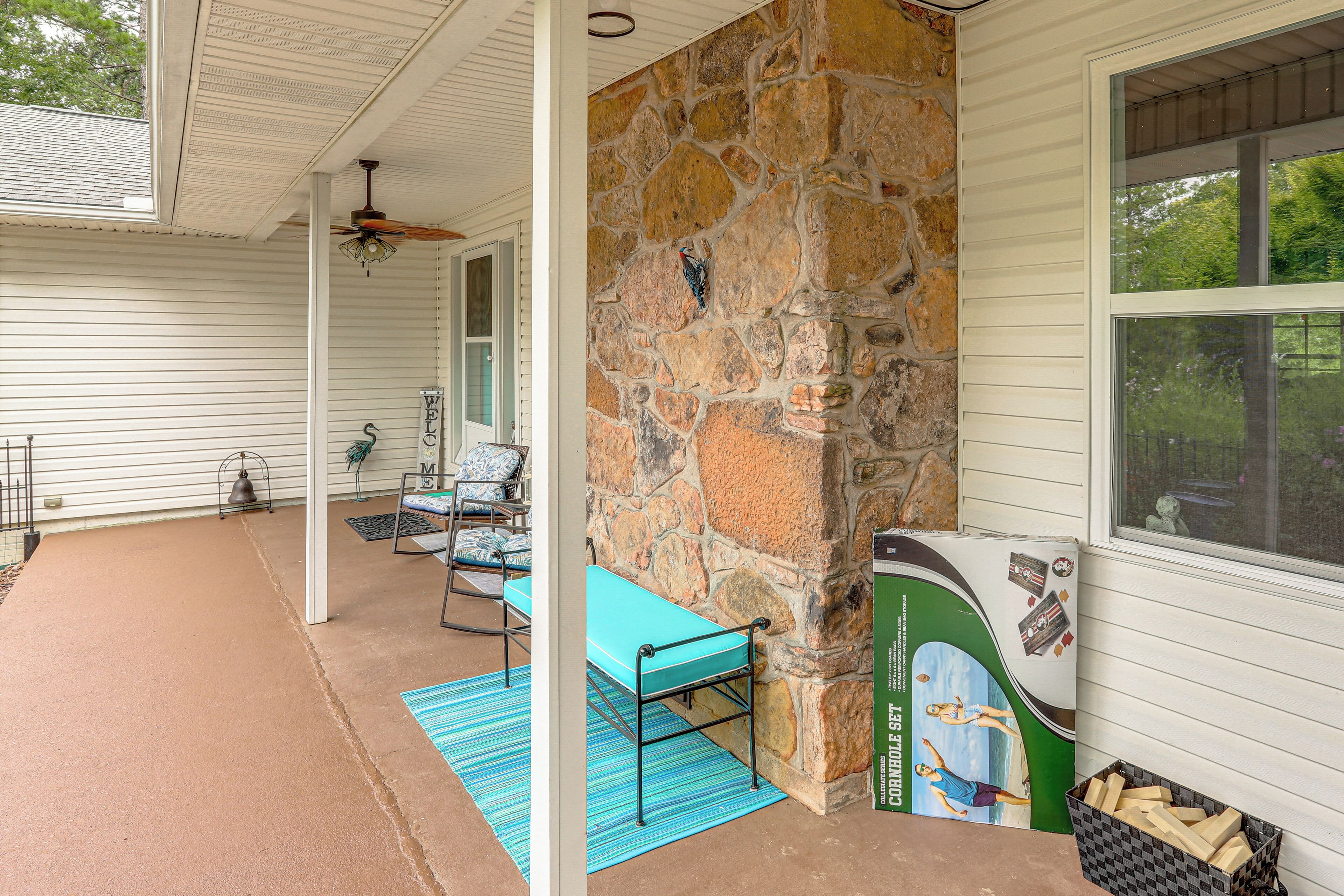 A covered porch with a stone wall, a blue bench, and a table with chairs.