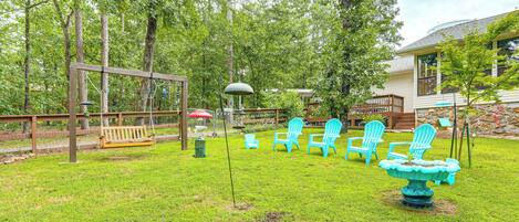 A backyard with a swing set, Adirondack chairs, and a bird bath.