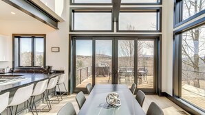 Une cuisine moderne avec un coin bar, de grandes fenêtres et une table à manger avec des chaises.