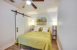 Ein Schlafzimmer mit einem Bett, einem Deckenventilator, einem Bild an der Wand und Nachttischlampen.