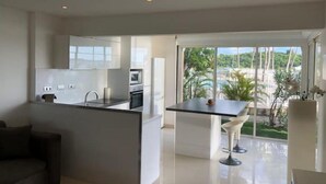 Una cucina moderna con mobili bianchi e un'area pranzo con tavolo nero e sedie bianche.