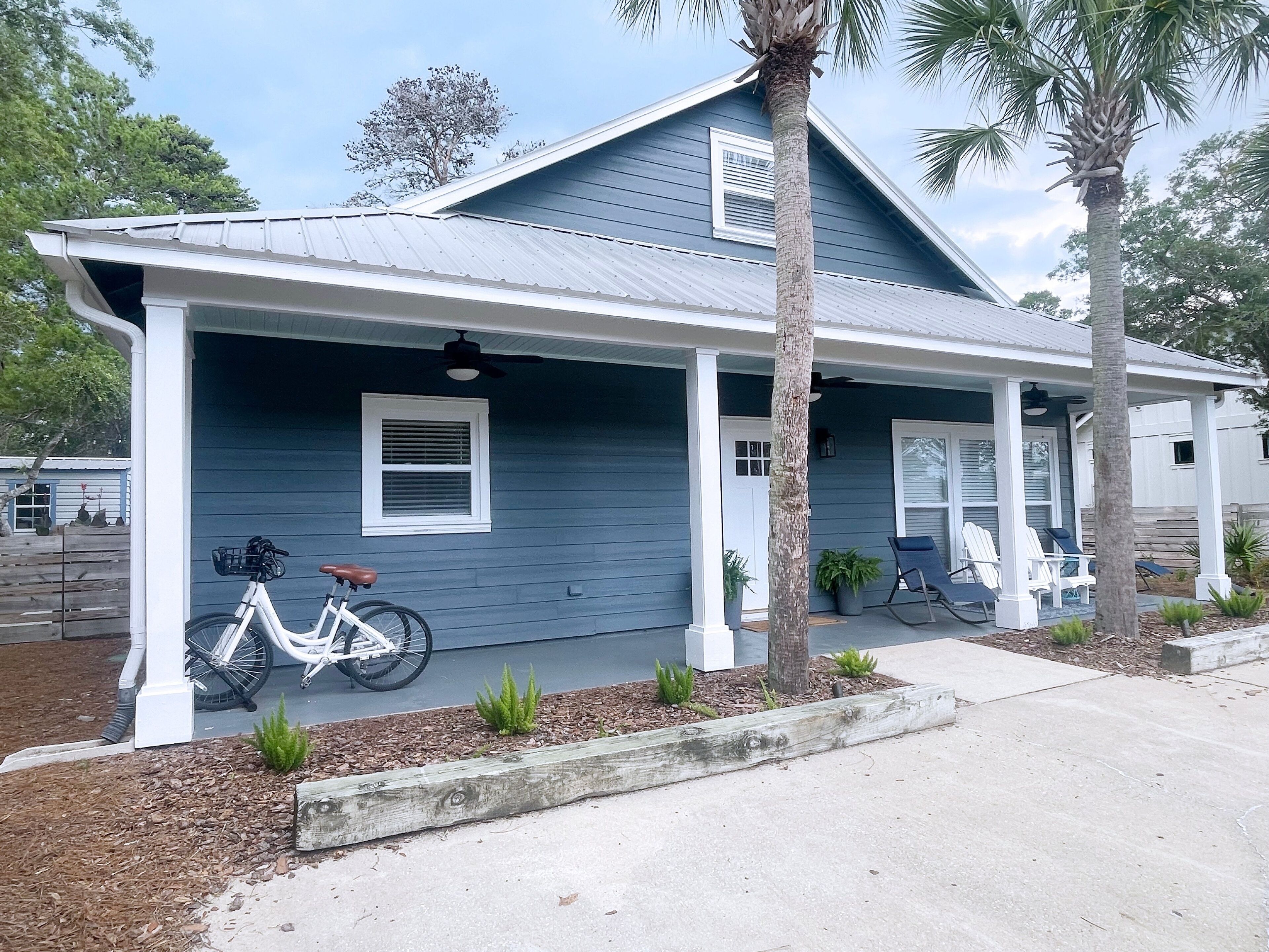 A two-story house with a porch, a bicycle, and a palm tree.