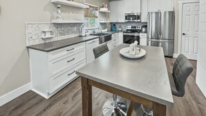 A modern kitchen with white cabinetry, stainless steel appliances, and a marble countertop. - Pinewood Cottage 2 Bedroom Home by RedAwning (Panama City Beach)