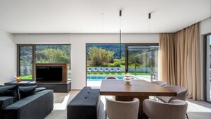 A modern living room with a TV, sofa, dining table, and chairs. - Casa Yiava with private pool (Ialysos, Dodecanese)