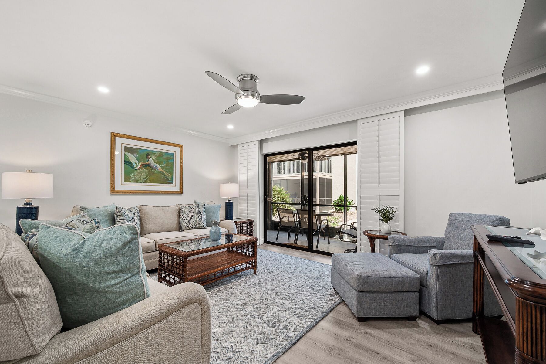 A living room with a sofa, armchair, coffee table, and a ceiling fan.