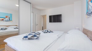 A modern hotel room with a wooden bed, white linens, a flat-screen TV, and a painting on the wall. - Villa Kristina (Nin)