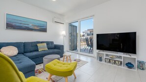 A modern living room with a blue sofa, a yellow armchair, a flat-screen TV, and a large window. - Villa Kristina (Nin)