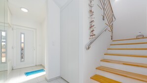 A staircase with wooden steps and a metal handrail, leading to a door with a glass panel. - Villa Kristina (Nin)