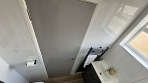 A compact bathroom with a toilet, sink, and towel rack. - The New England Hotel (Boston)