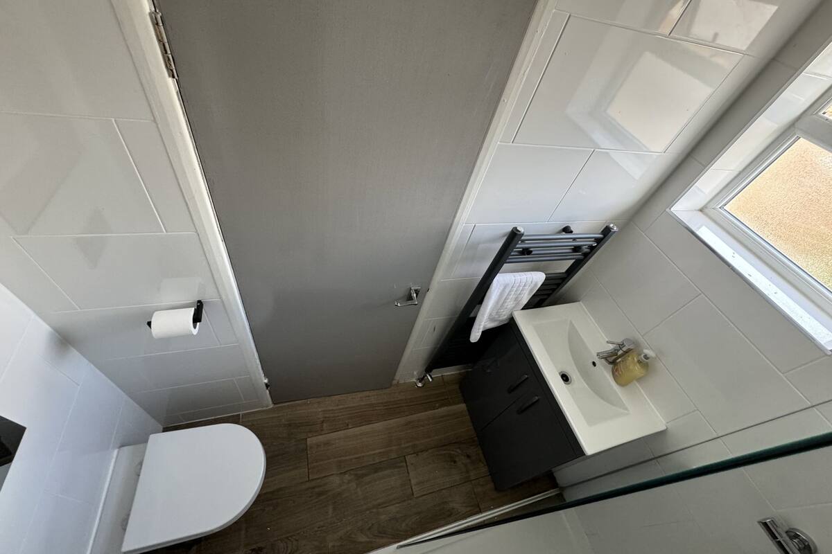 A compact bathroom with a toilet, sink, and towel rack.