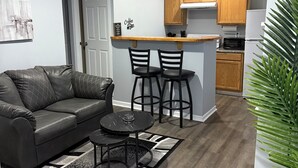 A compact living space with a sofa, a coffee bar, and a kitchen area.