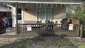 A house with a covered porch, a table and chairs, and a grill.