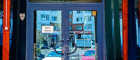 The entrance of the KOHAT YI HOTEL with a wooden ceiling, a glass door with a view of the street, and a sign indicating the hotel's name.