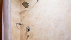 Un espacio de ducha con cabezal de ducha de mano, grifo empotrado y un plato de ducha.