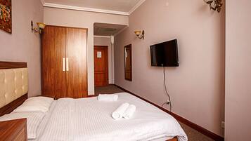 Una habitación de hotel con una cama, un televisor y un armario de madera.