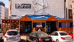 Un edificio con un gran mural de un velero, un letrero que dice 'Kopcap' y un restaurante 'Kopcap' con fachada de madera tradicional.