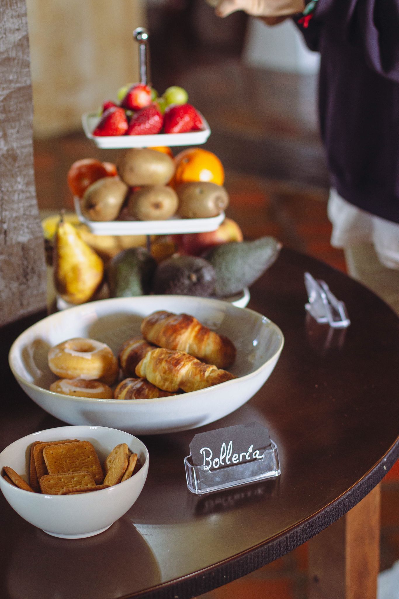 Una mesa de buffet con diversos alimentos, entre ellos frutas, bollería y galletas.