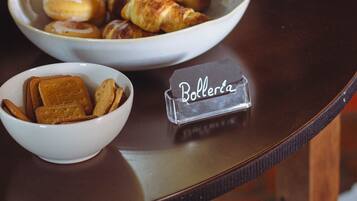 Una mesa de buffet con diversos alimentos, entre ellos frutas, bollería y galletas.
