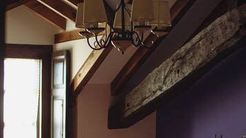 A bedroom with two beds, wooden beams, a hanging lamp, and a window.