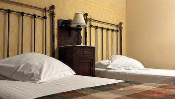 A hotel room with two beds, a nightstand, a lamp, and a patterned wall.