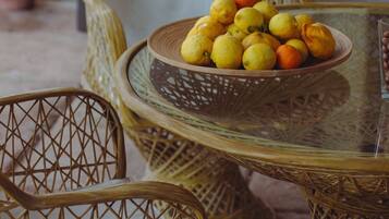 Wicker chairs and a glass table with a bowl of lemons and oranges.