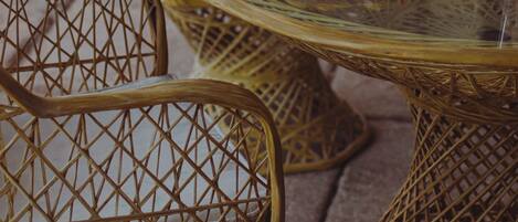 Wicker chairs and a glass table with a bowl of lemons and oranges.