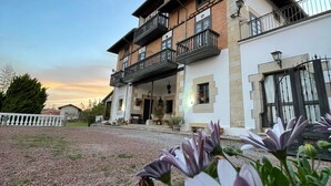Un bâtiment à deux étages doté d’un balcon, d’une façade en pierre et d’une allée gravillonnée.