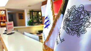 A reception desk with flags and a sign indicating a check-in area. - Hotel St Telemly (Algiers)