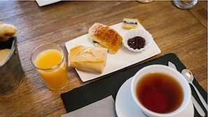 A breakfast setting with a plate of pastries, a glass of orange juice, and a cup of tea on a wooden table. - Hotel St Telemly (Algiers)