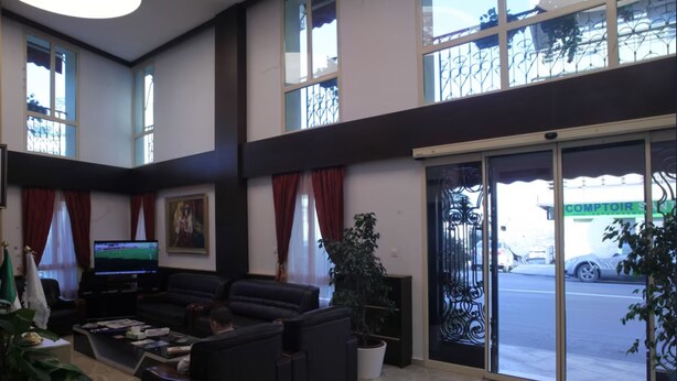 A spacious lobby with a large seating area, a television, and a view of the street through a glass door. - Hotel St Telemly (Algiers)