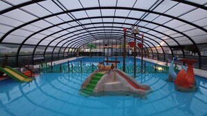 Una piscina interior con toboganes y una estructura para escalar.