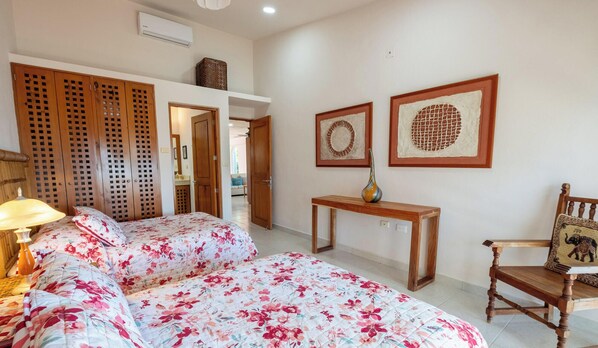 A bedroom with two beds, a wooden desk, and a chair. - Upscale beautiful beachfront villa with pool, AC and WiFi! (Akumal)