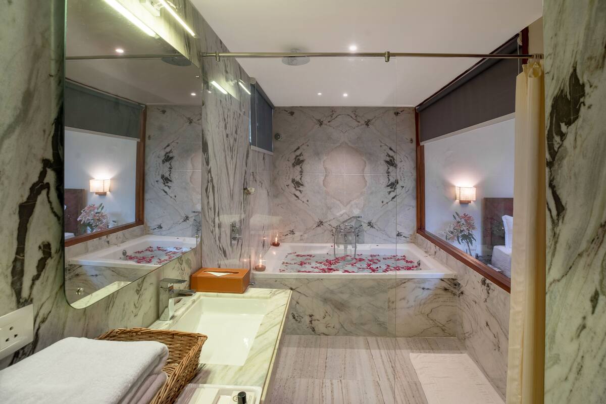 A bathroom with a marble floor, a bathtub, and a large mirror.