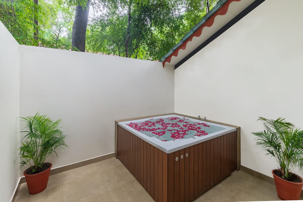 A spa area with a wooden tub, potted plants, and a view of trees.
