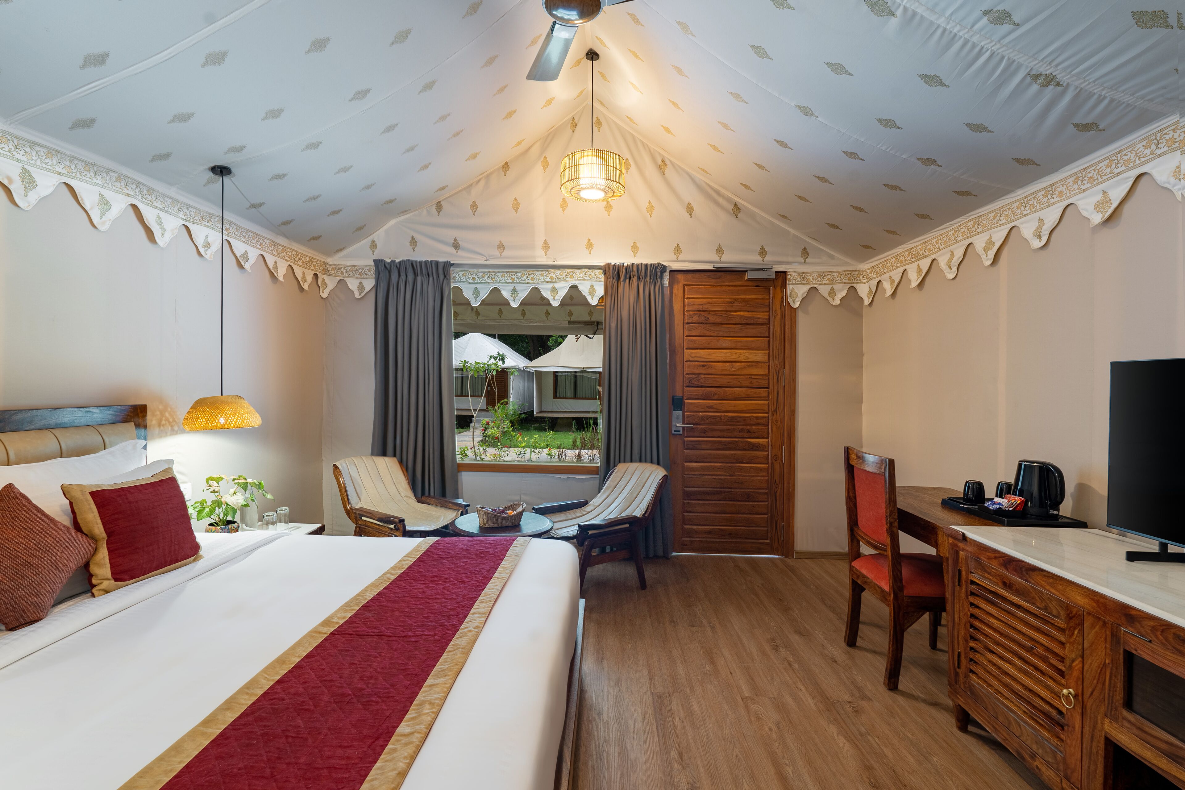 A hotel room with a large bed, a desk with a television, a chair, and a view of the outdoors.
