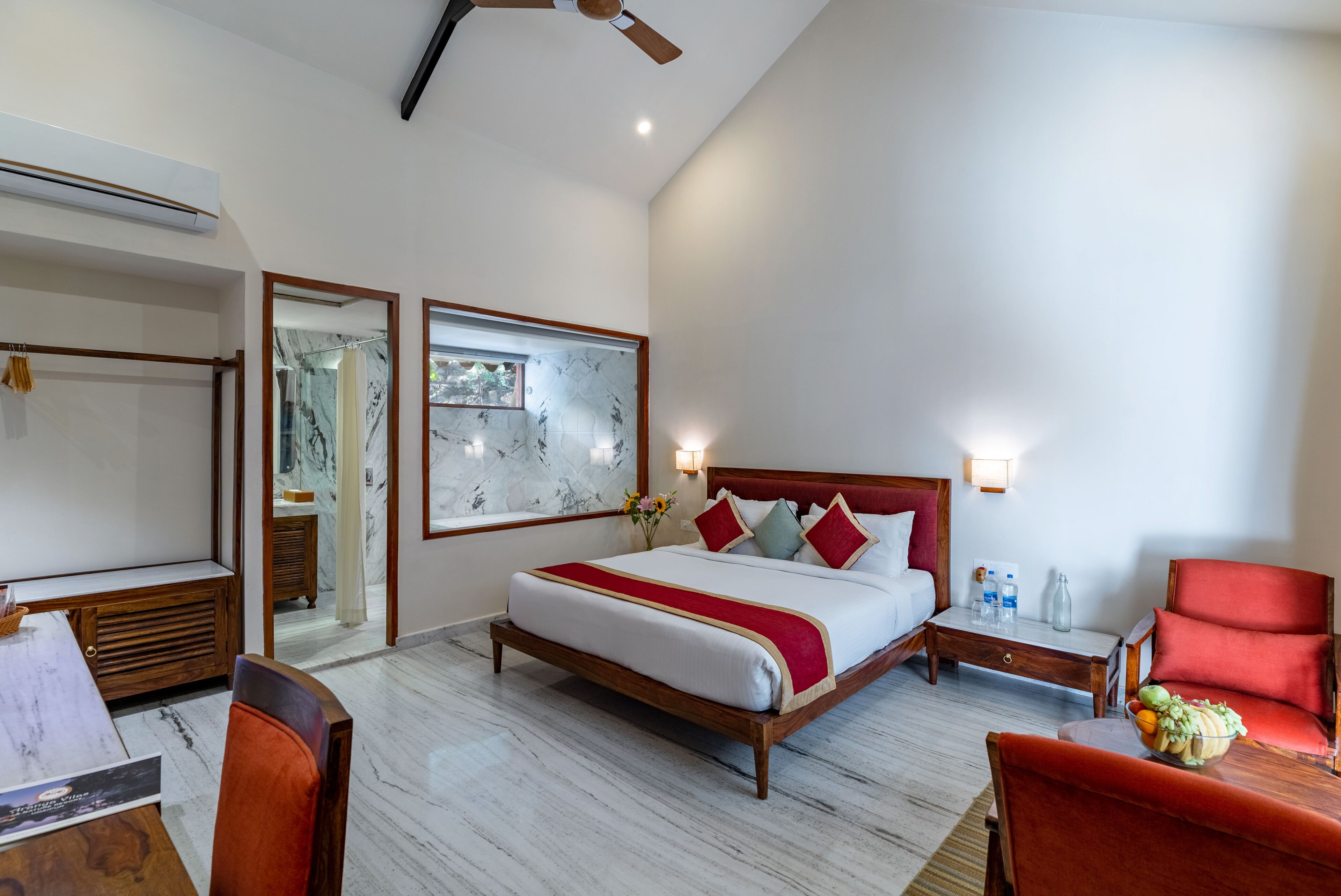 Ein Hotelzimmer mit Bett, Schreibtisch, Stuhl und einem roten Sessel.
